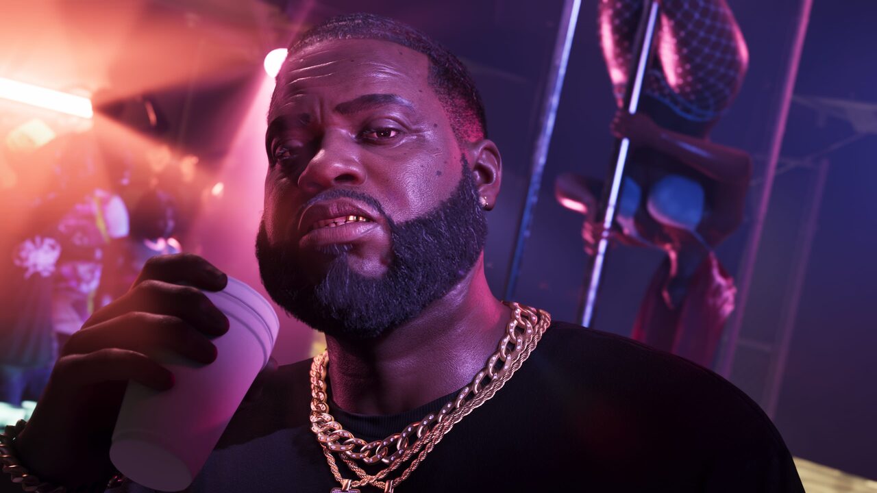 Boobie Ike drinking from a cup in a dim club, a dancer on a pole behind him.