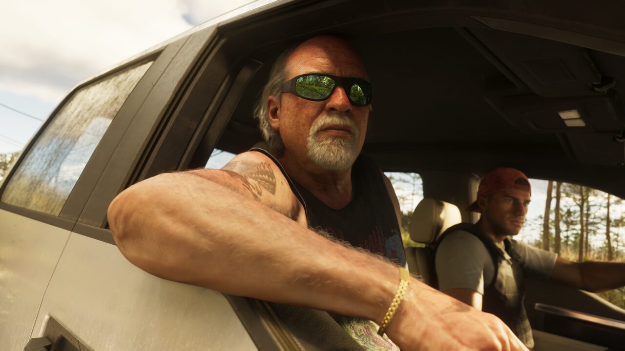 Brian Heder leaning out of a truck window in sunglasses, a passenger beside him on a wooded road.