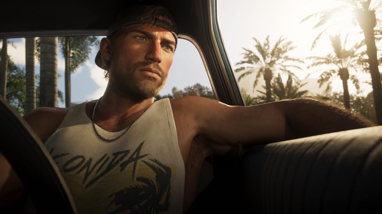 Jason Duval reclining in the back seat of a car, one arm out the open window, wearing a backwards cap and a Leonida-print tank top with palm trees outside.