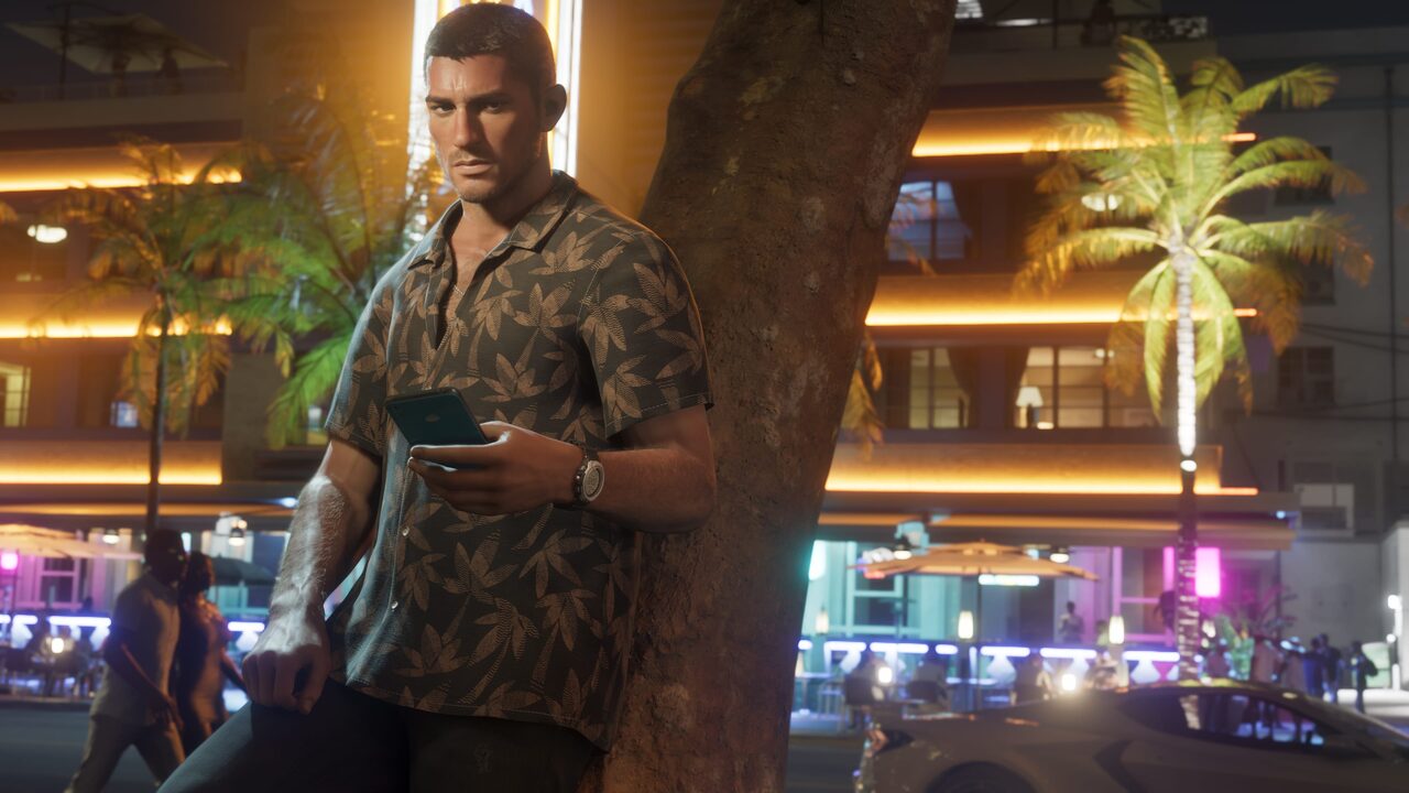 Jason Duval leaning against a palm tree at night, checking his phone, neon-lit hotel signage behind him.