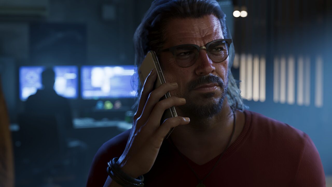 Raul Bautista taking a phone call in a dark room, monitors glowing behind him.