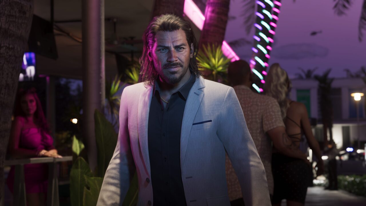 Raul Bautista in a light suit outside a nightclub at night, palm trees and neon lighting behind him.