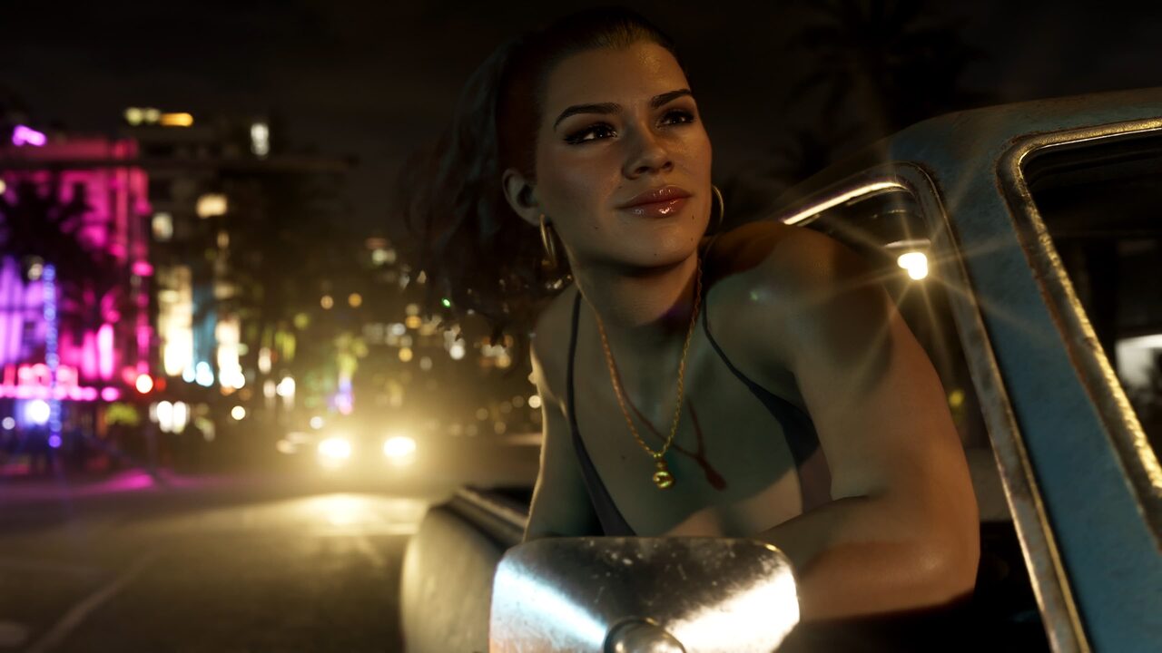 Lucia Caminos leaning out of a pickup truck window at night and smiling, with neon-lit buildings and headlights on the street behind her.