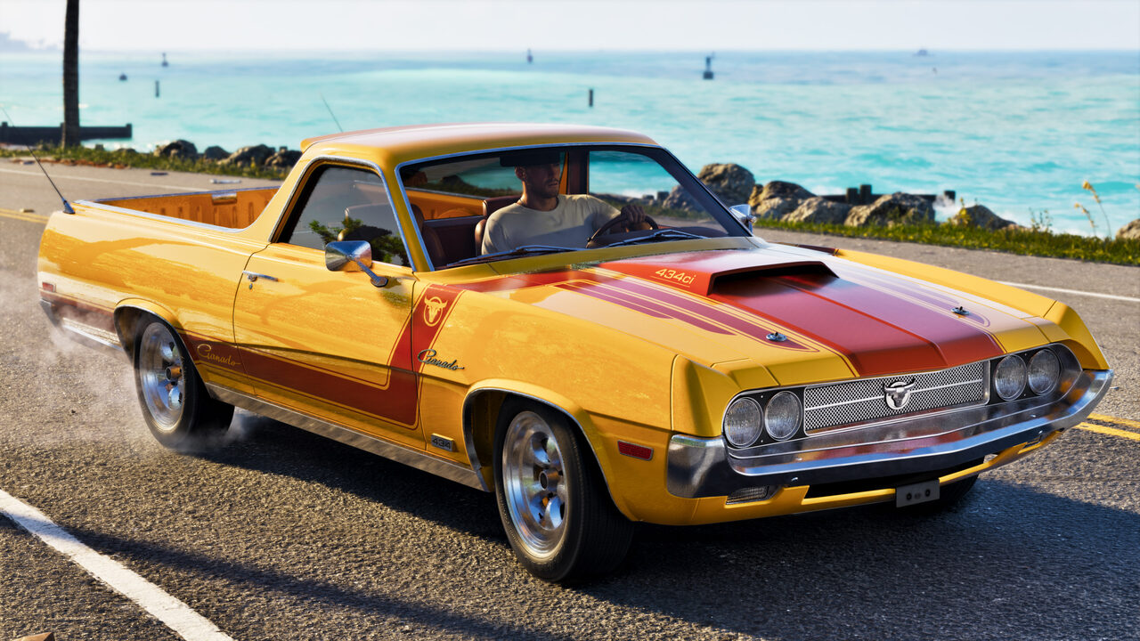 A yellow and red striped Ganado coupe utility driving a coastal road, a man at the wheel and turquoise water behind.