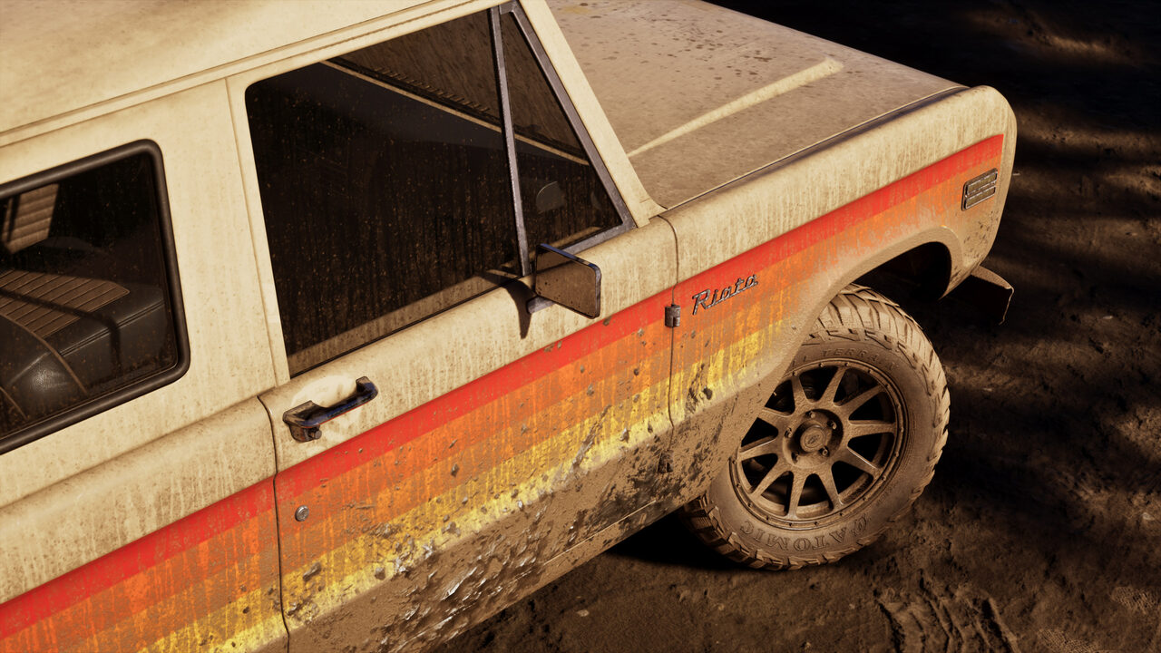 Side detail of a mud-caked cream pickup with a red and orange stripe along its flank, parked on churned ground.