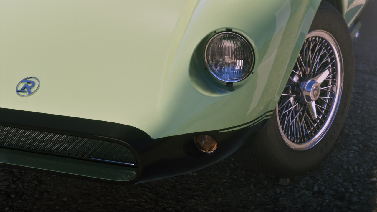 Close front detail of a pale green classic sports car with a round headlight and chrome wire-spoke wheel.