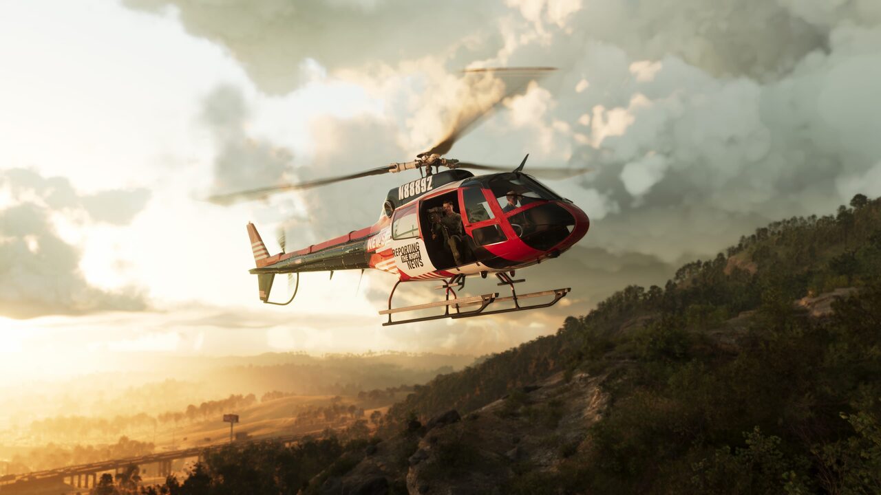 A red and white news helicopter banking over a wooded ridge at sunset, a cameraman leaning out of the open side door.