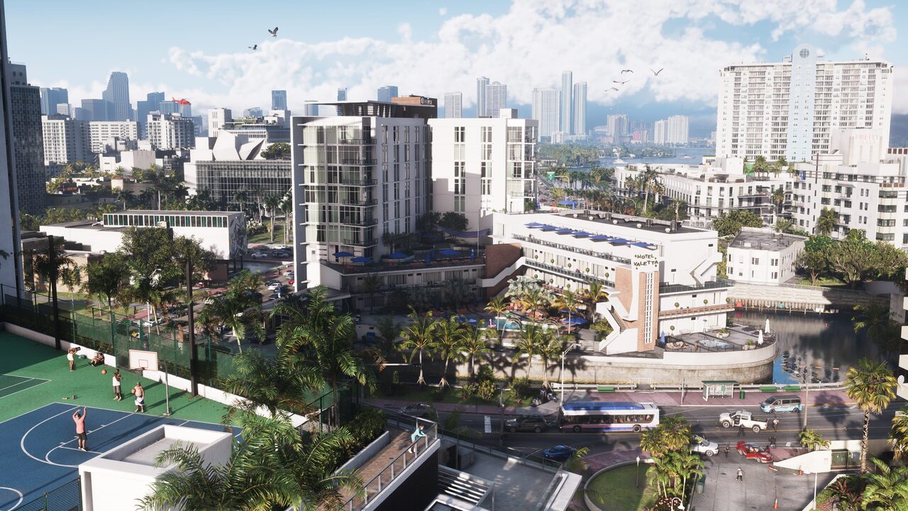 A daytime aerial over a Vice City hotel district: mid-rise blocks, a rooftop basketball court, a bus on the boulevard and towers on the skyline behind.